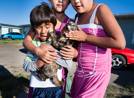 Children pose with an uncooperative kitten. Browning, Blackfeet Reservation, Montana. Backyard, Browning Montana
